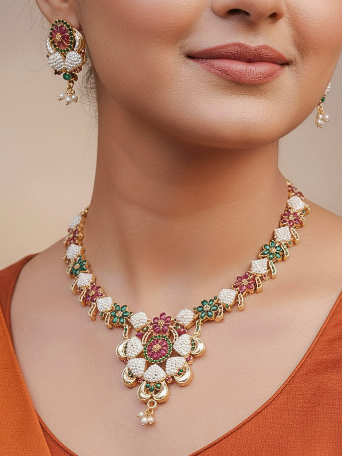 Close-up of a woman wearing an ornate traditional (Bright Gold Polish) Red,Green and White Collar jewellery set and earrings and Ring with Pearls and Red & Green Colored Stones. Mehendi ceremony look completed with a handcrafted Pearl jewelry set. Woman wearing a vibrant Pearl artificial jewelry set for celebrations.