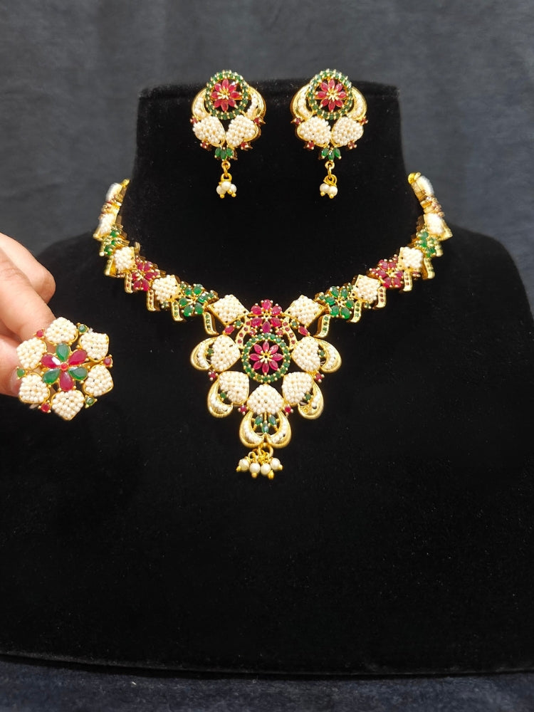 Close-up of an ornate traditional (Bright Gold Polish) Red,Green and White Collar jewellery set and earrings and Ring with Pearls and Red & Green Colored Stones. Mehendi ceremony look completed with a handcrafted Pearl jewelry set. Woman wearing a vibrant Pearl artificial jewelry set for celebrations.