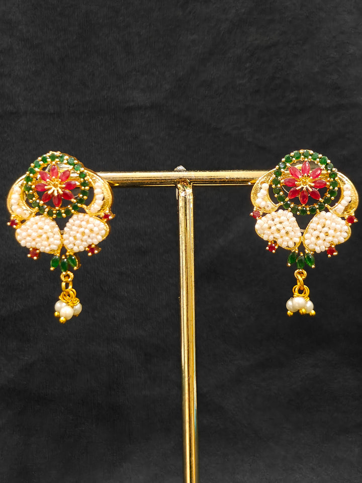 Close-up of an ornate traditional (Bright Gold Polish) Red,Green and White Collar jewellery set and earrings and Ring with Pearls and Red & Green Colored Stones. Mehendi ceremony look completed with a handcrafted Pearl jewelry set. Woman wearing a vibrant Pearl artificial jewelry set for celebrations.