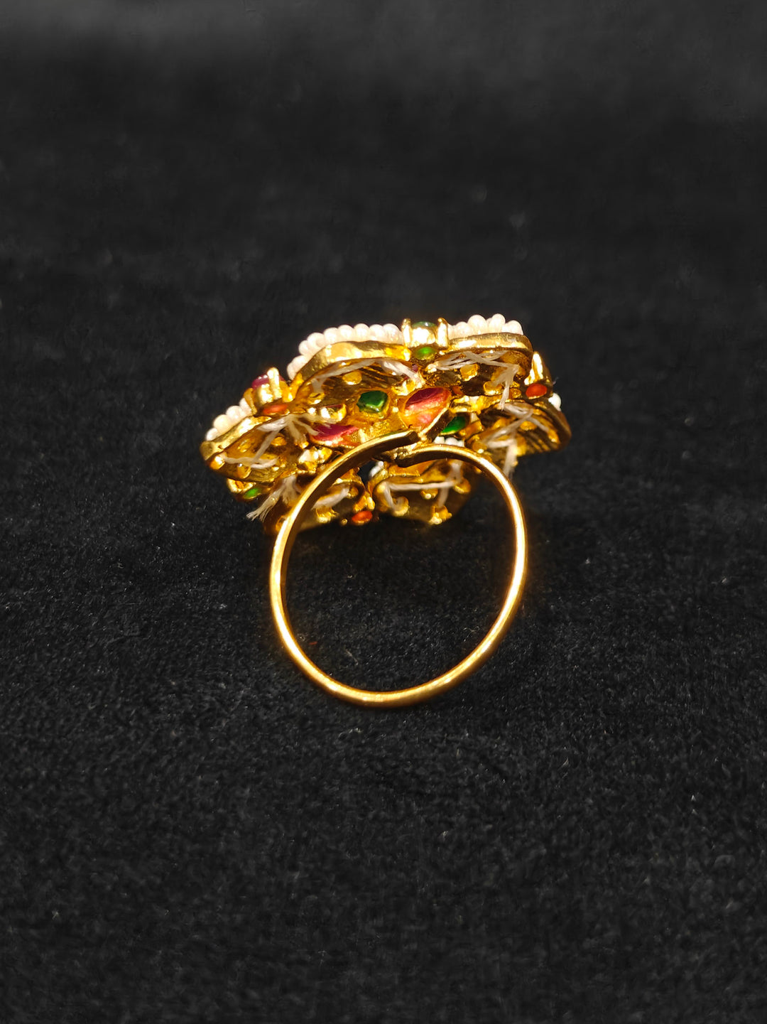 Close-up of an ornate traditional (Bright Gold Polish) Red,Green and White Collar jewellery set and earrings and Ring with Pearls and Red & Green Colored Stones. Mehendi ceremony look completed with a handcrafted Pearl jewelry set. Woman wearing a vibrant Pearl artificial jewelry set for celebrations.