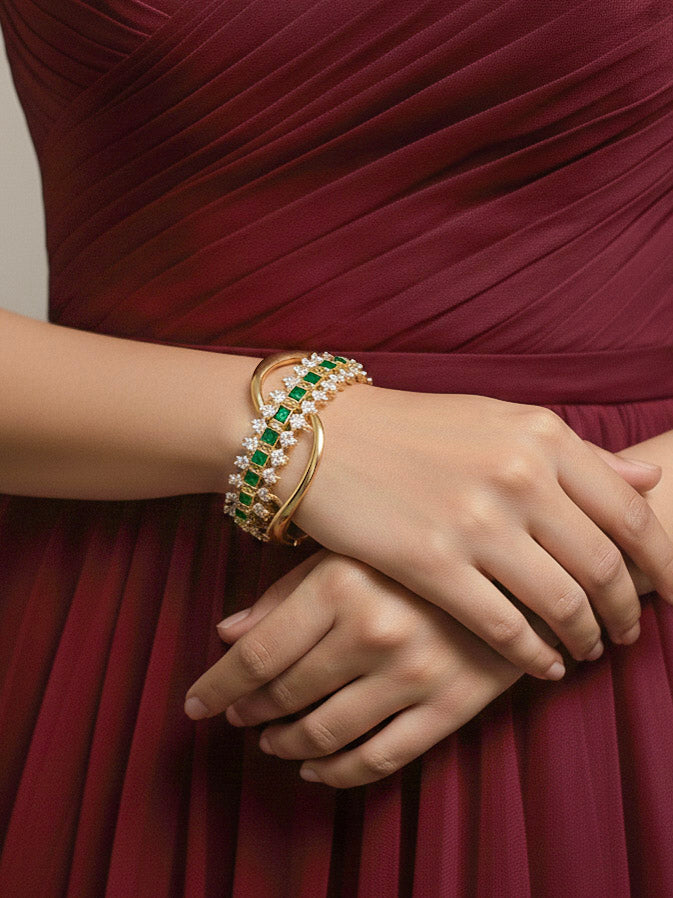 Close-up of a woman wearing an ornate Indo-western Green (Bright gold) Diamond Bracelet with American Diamond and Colored Stones. Woman wearing a sparkling American diamond artificial bracelet for a party. Close-up of an anti-tarnish artificial American Diamond bracelet styled for wedding guests.