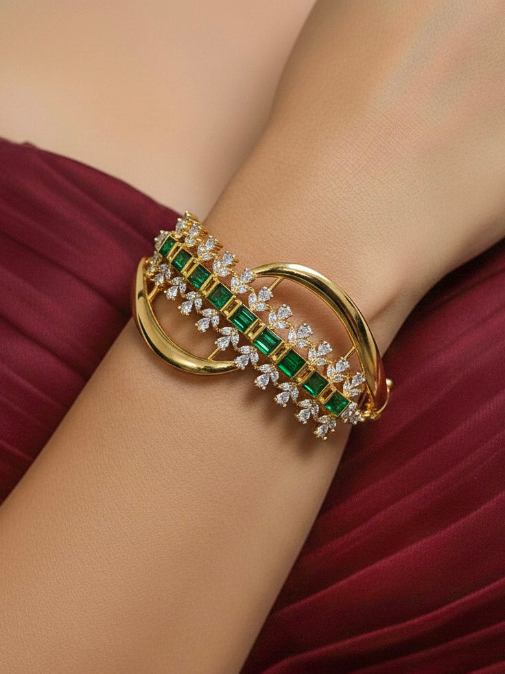 Close-up of a woman wearing an ornate Indo-western Green (Bright gold) Diamond Bracelet with American Diamond and Colored Stones. Woman wearing a sparkling American diamond artificial bracelet for a party. Close-up of an anti-tarnish artificial American Diamond bracelet styled for wedding guests.