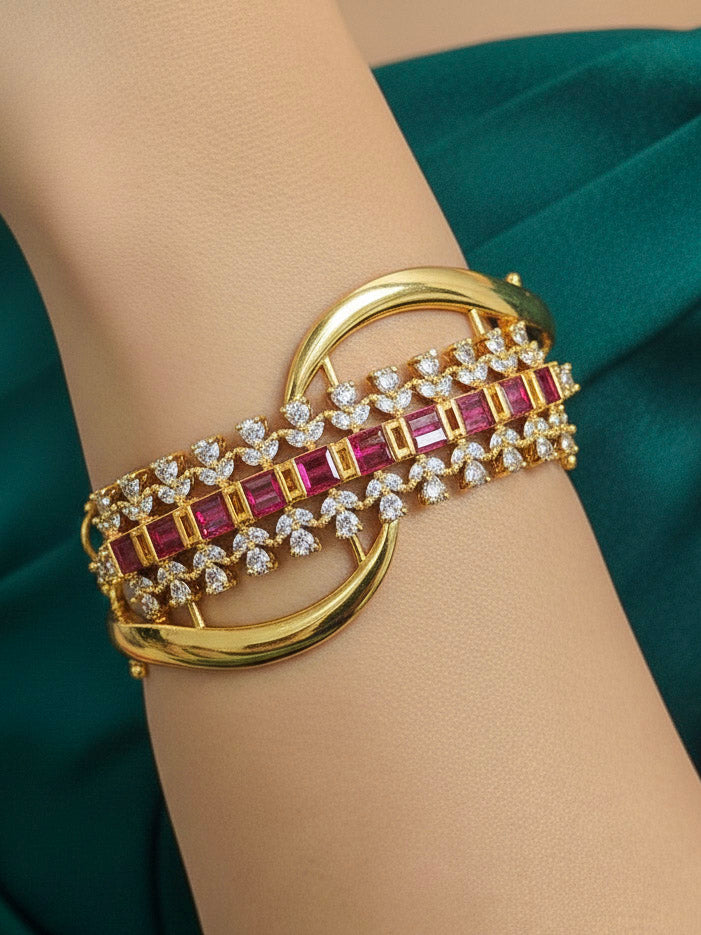 Close-up of a woman wearing an ornate Indo-western Pink (Bright gold) Diamond Bracelet with American Diamond and Colored Stones. Woman wearing a sparkling American diamond artificial bracelet for a party. Close-up of an anti-tarnish artificial American Diamond bracelet styled for wedding guests.