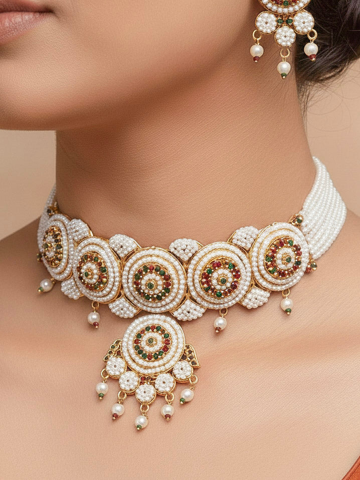 Close-up of a women wearing an ornate traditional (Bright Gold Polish) Red,Green and White Choker jewellery set and earrings and Ring with Pearls and Red & Green Colored Stones. Mehendi ceremony look completed with a handcrafted Pearl jewelry set. Woman wearing a vibrant Pearl artificial jewelry set for celebrations.