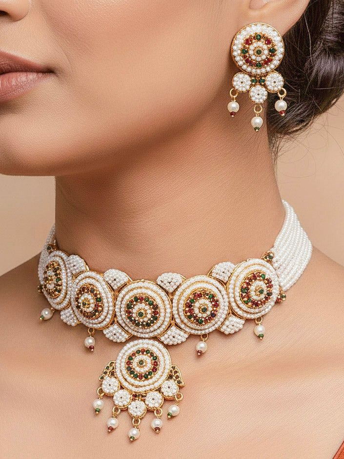 Close-up of a women wearing an ornate traditional (Bright Gold Polish) Red,Green and White Choker jewellery set and earrings and Ring with Pearls and Red & Green Colored Stones. Mehendi ceremony look completed with a handcrafted Pearl jewelry set. Woman wearing a vibrant Pearl artificial jewelry set for celebrations.