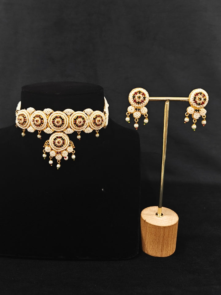 Close-up of an ornate traditional (Bright Gold Polish) Red,Green and White Choker jewellery set and earrings and Ring with Pearls and Red & Green Colored Stones. Mehendi ceremony look completed with a handcrafted Pearl jewelry set. Woman wearing a vibrant Pearl artificial jewelry set for celebrations.