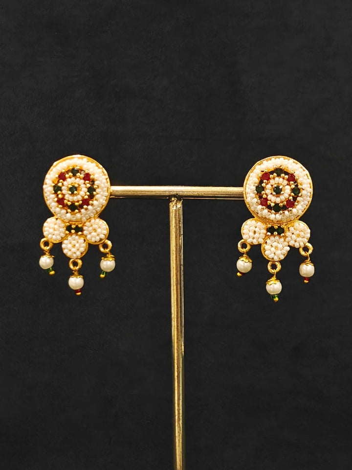 Close-up of an ornate traditional (Bright Gold Polish) Red,Green and White Choker jewellery set and earrings and Ring with Pearls and Red & Green Colored Stones. Mehendi ceremony look completed with a handcrafted Pearl jewelry set. Woman wearing a vibrant Pearl artificial jewelry set for celebrations.