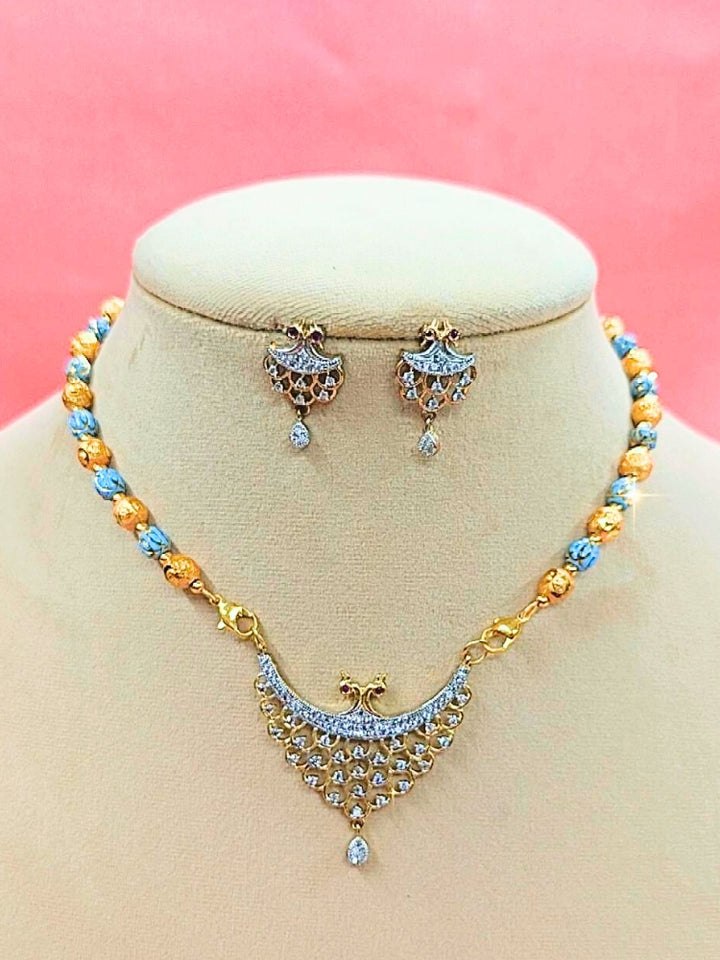 Niharika Mangalsutra—a gold necklace with black mangalsutra beads and matching earrings, pendant featuring sparkling American Diamonds—set against a cream dummy, perfect for your wedding ceremony dress. Diamond mangalsutra. Modern mangalsutra. 