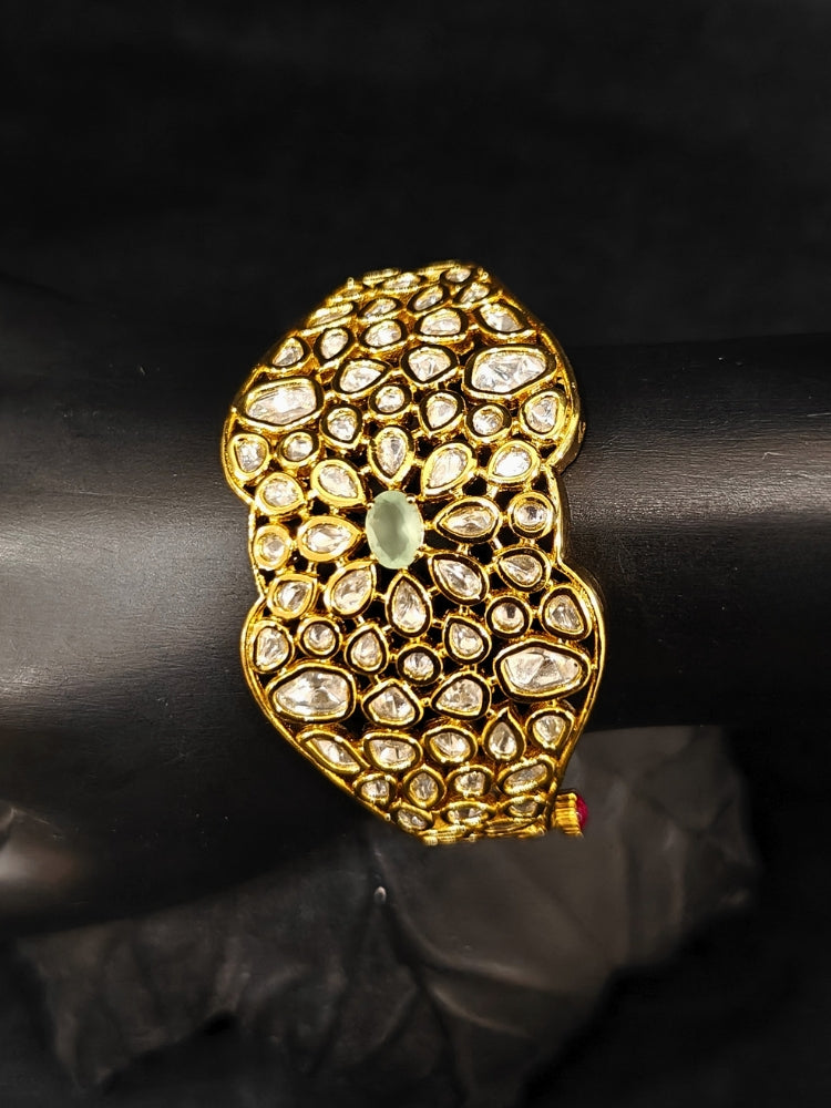 Close-up of an ornate traditional (Gold Polish) White Bracelet with Polki and Mint Green Colored Stone in Middle. Woman stacking artificial Polki Bracelet for a festive Diwali celebration. Close-up of an anti-tarnish artificial Polki bracelet styled for wedding guests.