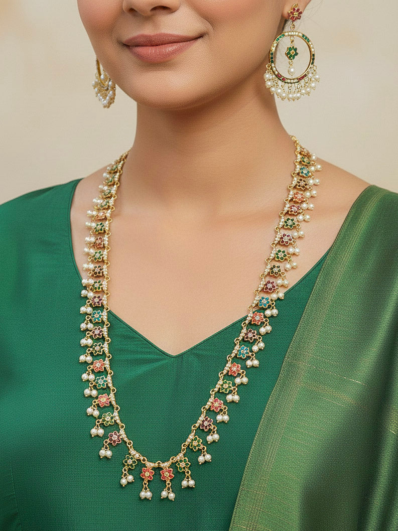 Close-up of a woman wearing an ornate traditional Long jadau gold jewellery set and  jadau earrings with pearls and gemstones. Perfect Jadau necklace set for weddings and festivals. 