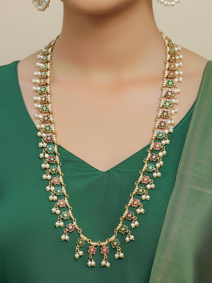 Close-up of a woman wearing a gold Indian traditional Long jadau jewellery with pearls and multicolor jadau stones, and matching jadau earrings. This authentic jadau jewelry set can we worn as jadau necklace set for weddings. 