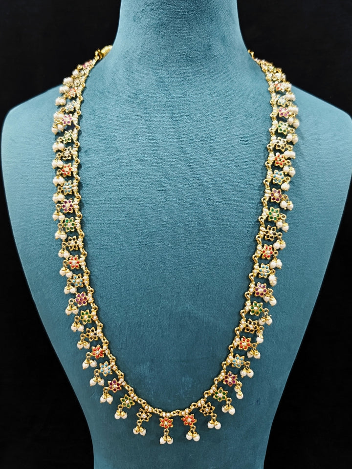 Close-up of an ornate handmade jadau jewelry set and earrings with multicolor jadau gemstones. This is a perfect long jadau jewelry set for weddings, festivals and more. Can also be worn as bridal long jadau jewelry for indian weddings. 