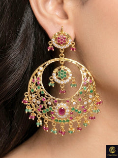 Close-up of a woman wearing an ornate traditional Ruby Pink and Green jadau gold earrings with Beads and Color Stone. Elegant festive wear styled with high-quality imitation Jadau earrings. Perfect Jadau Earrings set for weddings and festivals.
