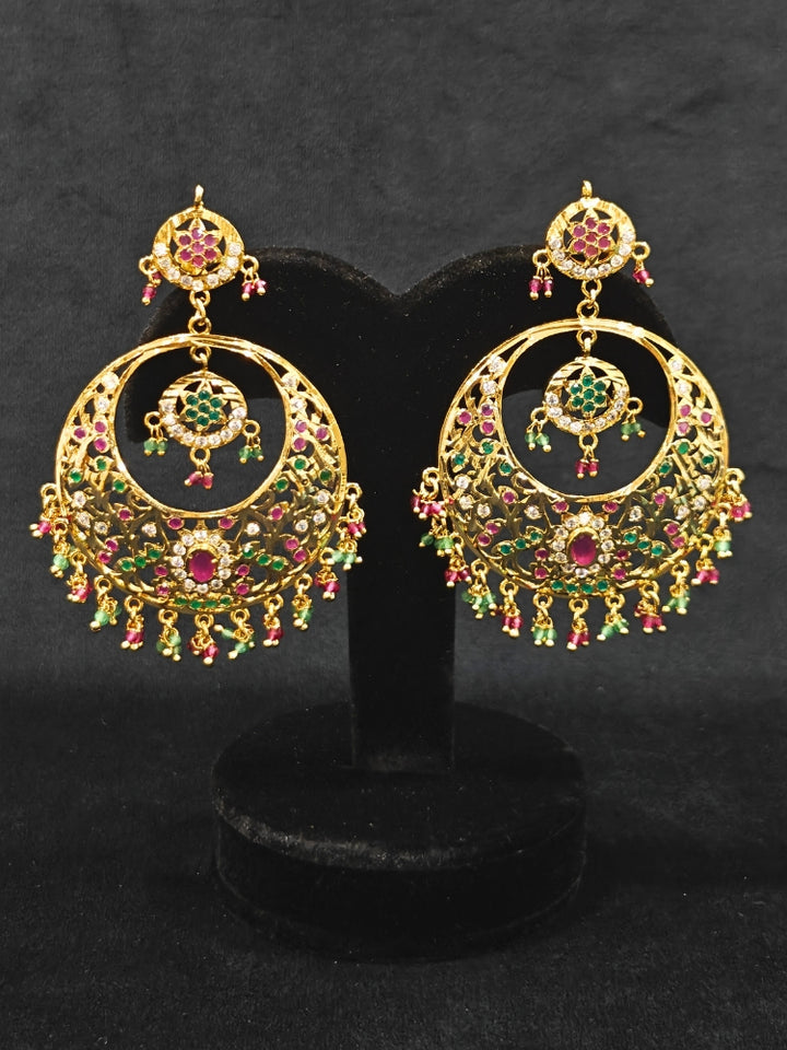 Close-up of an ornate traditional Ruby Pink and Green jadau gold earrings with Beads and Color Stone. Elegant festive wear styled with high-quality imitation Jadau earrings. Perfect Jadau Earrings set for weddings and festivals.