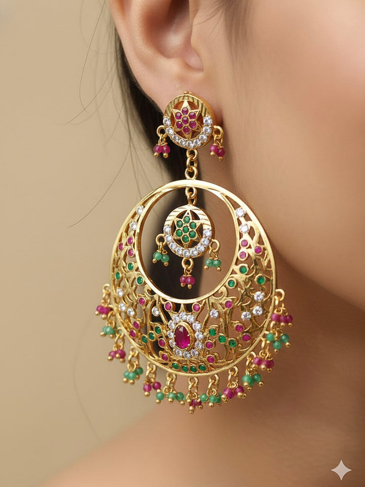 Close-up of a woman wearing an ornate traditional Ruby Pink and Green jadau gold earrings with Beads and Color Stone. Elegant festive wear styled with high-quality imitation Jadau earrings. Perfect Jadau Earrings set for weddings and festivals.
