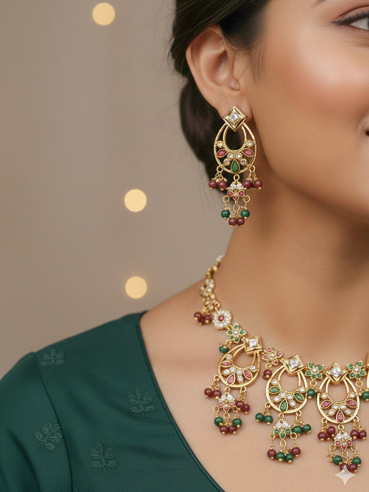 Close-up of a woman wearing an ornate traditional jadau gold jewellery set and jadau earrings with pearls and Ruby Pink & Green gemstones. Elegant  look featuring a luxury Jadau artificial jewelry set. Festive celebration look featuring a Jadau artificial necklace.