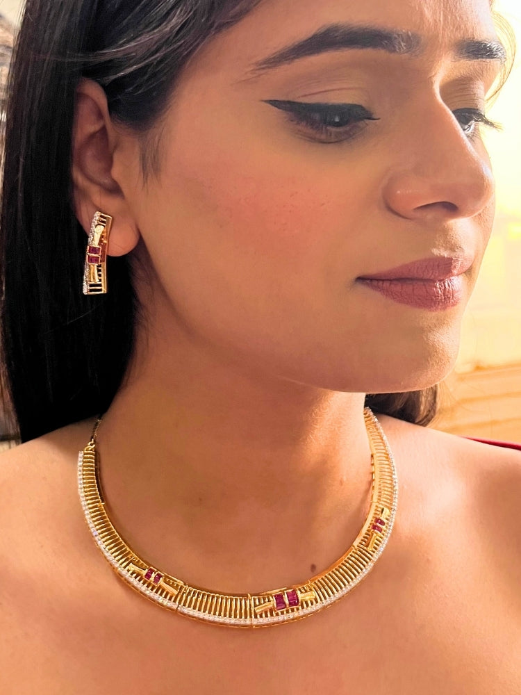 A woman wears the Noctelle Pink Necklace Set—gold with red and white diamond stones in a geometric design. The American Diamonds jewelry beautifully complements her warm skin tone and natural makeup.