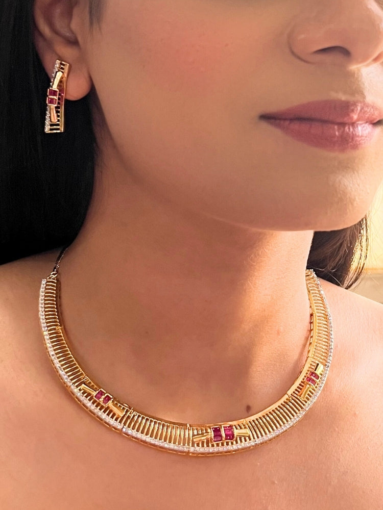 A woman wears the Noctelle Pink Necklace Set—gold with red and white diamond stones in a geometric design. The American Diamonds jewelry beautifully complements her warm skin tone and natural makeup.
