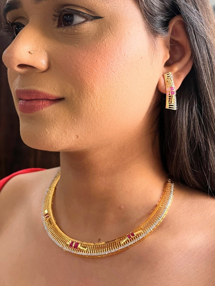 A woman wears the Noctelle Pink Necklace Set—gold with red and white diamond stones in a geometric design. The American Diamonds jewelry beautifully complements her warm skin tone and natural makeup.