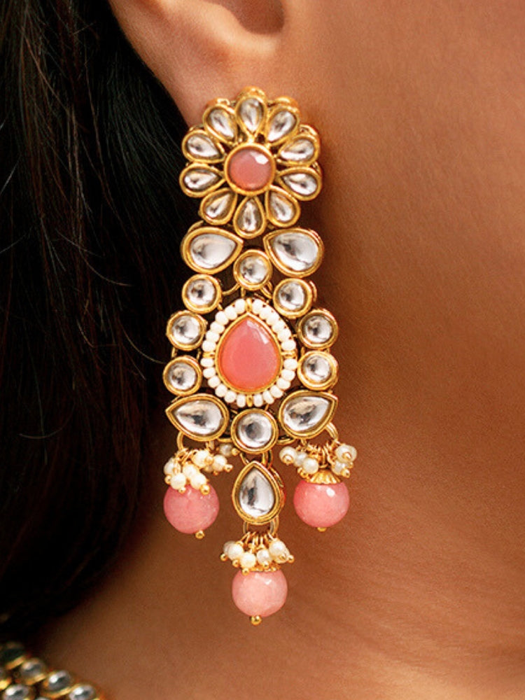 Close-up of a woman wearing an ornate traditional Pink Collar jewellery set and earrings and maangtikka with Kundan, Beads and Pearls. Royal bridal look featuring a traditional Kundan necklace set. Woman wearing trending Kundan artificial jewelry for wedding season in India. Close-up of intricate Kundan craftsmanship in artificial bridal jewelry.