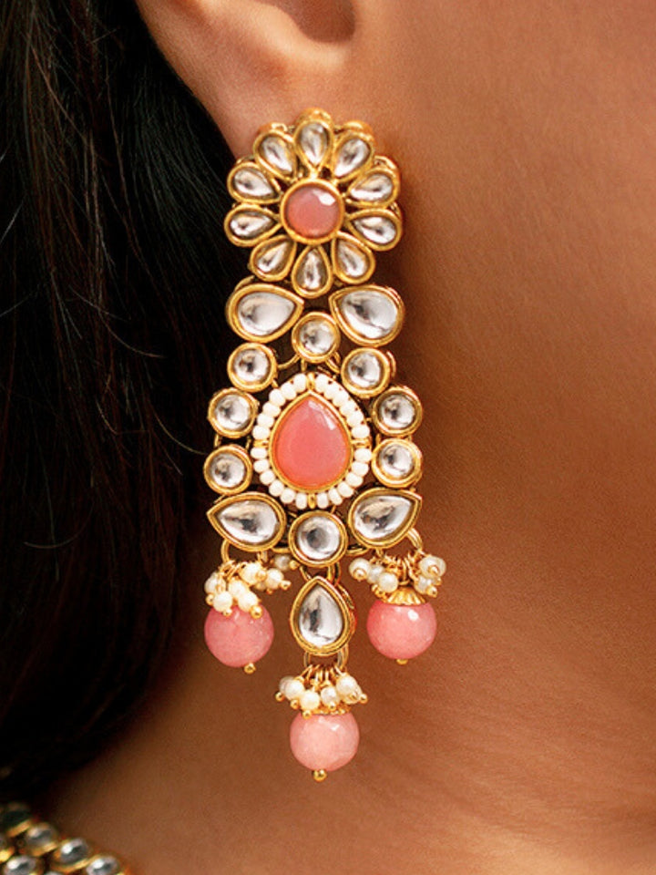 Close-up of a woman wearing an ornate traditional Pink Collar jewellery set and earrings and maangtikka with Kundan, Beads and Pearls. Royal bridal look featuring a traditional Kundan necklace set. Woman wearing trending Kundan artificial jewelry for wedding season in India. Close-up of intricate Kundan craftsmanship in artificial bridal jewelry.