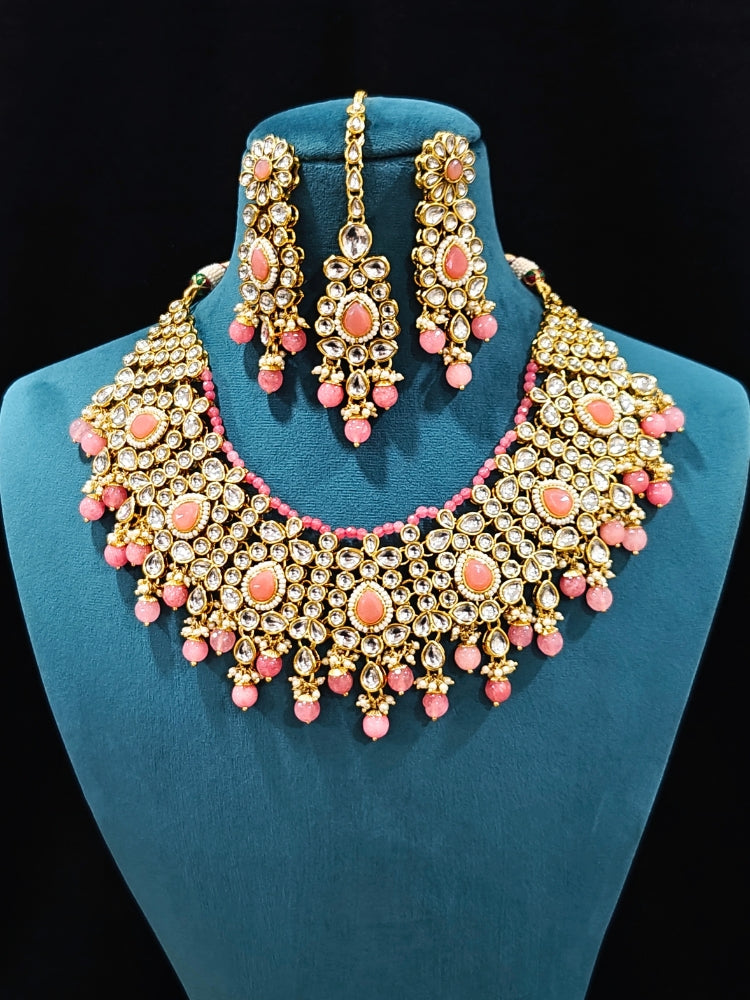 Close-up of an ornate traditional Pink Collar jewellery set and earrings and maangtikka with Kundan, Beads and Pearls. Royal bridal look featuring a traditional Kundan necklace set. A trending Kundan artificial jewelry for wedding season in India. Close-up of intricate Kundan craftsmanship in artificial bridal jewelry.