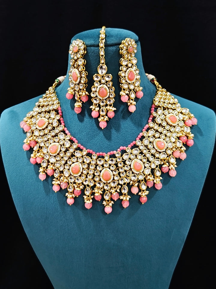 Close-up of an ornate traditional Pink Collar jewellery set and earrings and maangtikka with Kundan, Beads and Pearls. Royal bridal look featuring a traditional Kundan necklace set. A trending Kundan artificial jewelry for wedding season in India. Close-up of intricate Kundan craftsmanship in artificial bridal jewelry.