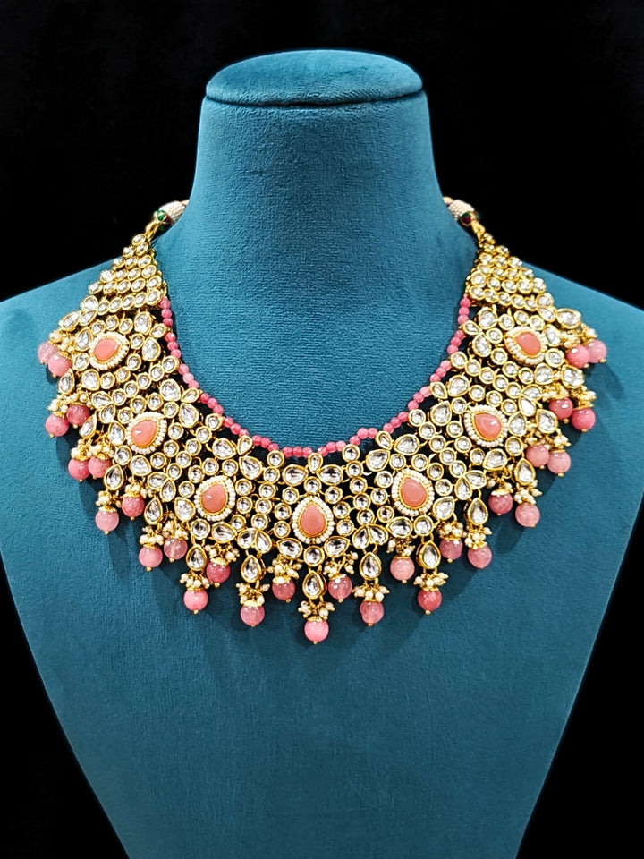 Close-up of an ornate traditional Pink Collar jewellery set and earrings and maangtikka with Kundan, Beads and Pearls. Royal bridal look featuring a traditional Kundan necklace set. A trending Kundan artificial jewelry for wedding season in India. Close-up of intricate Kundan craftsmanship in artificial bridal jewelry.
