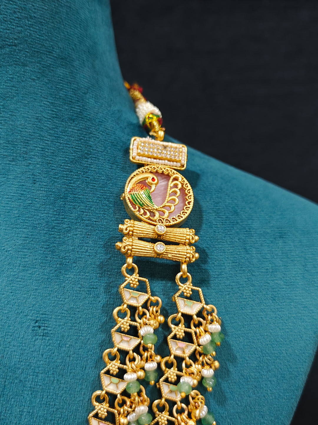 Close-up of an ornate traditional Mint Pink and Green Heritage gold Long Layered jewellery set and earrings with Colored Stones and Beads. Festive celebration outfit paired with a handcrafted heritage jewelry set. Festive  outfit styled with a royal heritage necklace. Festive celebration look enhanced with traditional Meenakari jewelry.
