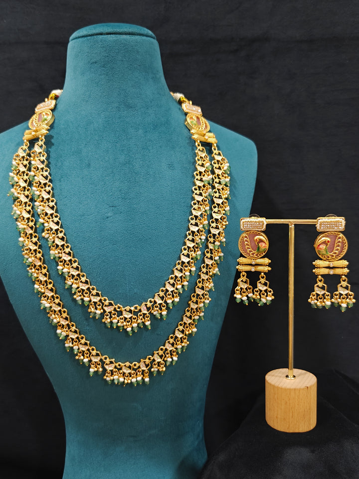 Close-up of an ornate traditional Mint Pink and Green Heritage gold Long Layered jewellery set and earrings with Colored Stones and Beads. Festive celebration outfit paired with a handcrafted heritage jewelry set. Festive  outfit styled with a royal heritage necklace. Festive celebration look enhanced with traditional Meenakari jewelry.