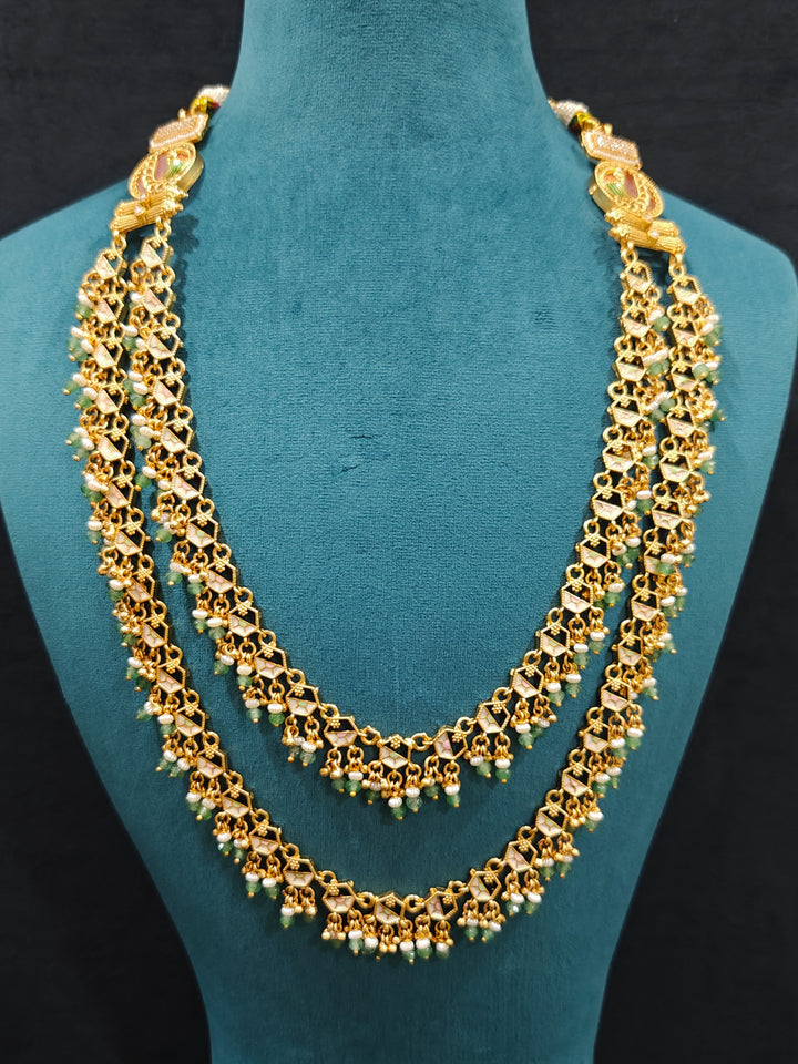 Close-up of an ornate traditional Mint Pink and Green Heritage gold Long Layered jewellery set and earrings with Colored Stones and Beads. Festive celebration outfit paired with a handcrafted heritage jewelry set. Festive  outfit styled with a royal heritage necklace. Festive celebration look enhanced with traditional Meenakari jewelry.
