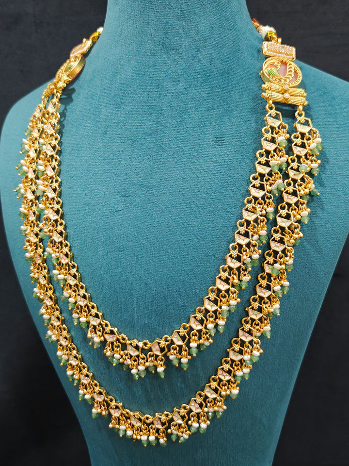 Close-up of an ornate traditional Mint Pink and Green Heritage gold Long Layered jewellery set and earrings with Colored Stones and Beads. Festive celebration outfit paired with a handcrafted heritage jewelry set. Festive  outfit styled with a royal heritage necklace. Festive celebration look enhanced with traditional Meenakari jewelry.