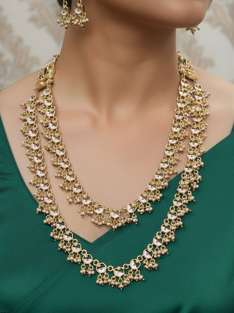 Close-up of a woman wearing an ornate traditional Dark Pink Heritage gold Long Layered jewellery set and earrings with Colored Stones and Beads. Festive celebration outfit paired with a handcrafted heritage jewelry set. Festive  outfit styled with a royal heritage necklace.