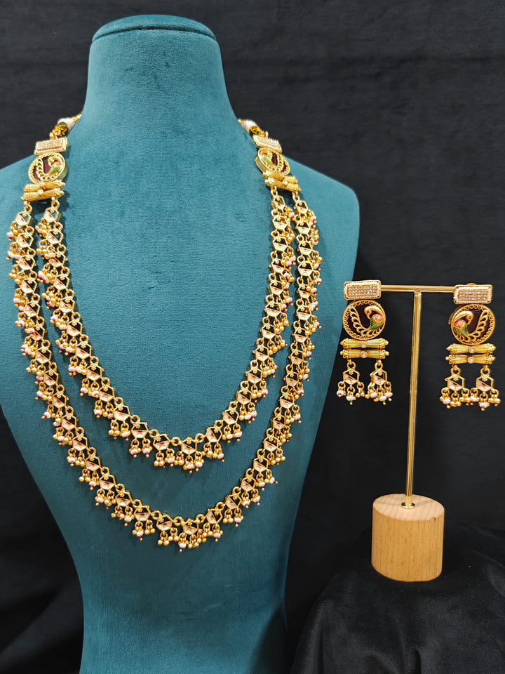 Close-up of an ornate traditional Dark Pink Heritage gold Long Layered jewellery set and earrings with Colored Stones and Beads. Festive celebration outfit paired with a handcrafted heritage jewelry set. Festive  outfit styled with a royal heritage necklace.