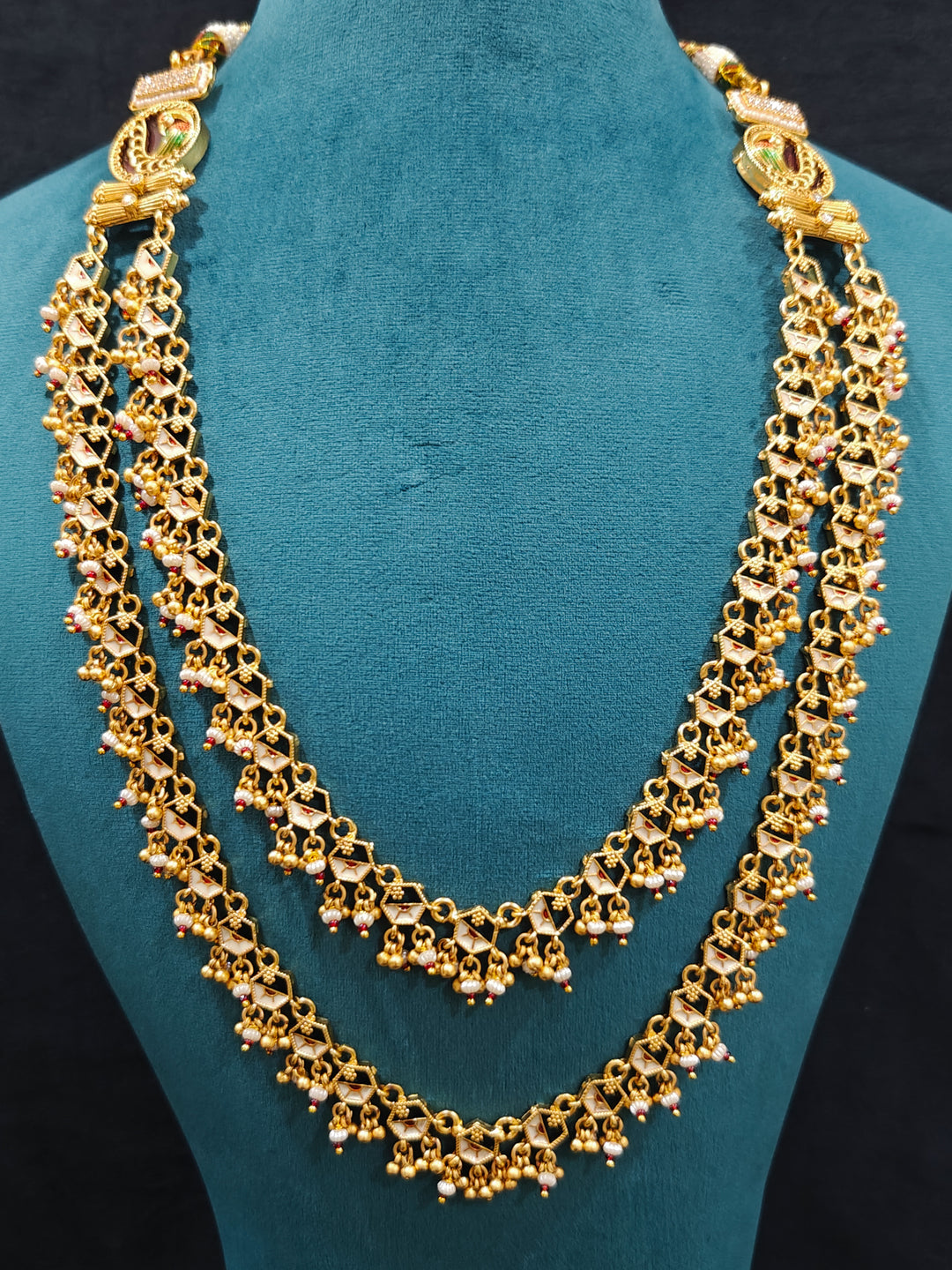 Close-up of an ornate traditional Dark Pink Heritage gold Long Layered jewellery set and earrings with Colored Stones and Beads. Festive celebration outfit paired with a handcrafted heritage jewelry set. Festive  outfit styled with a royal heritage necklace.