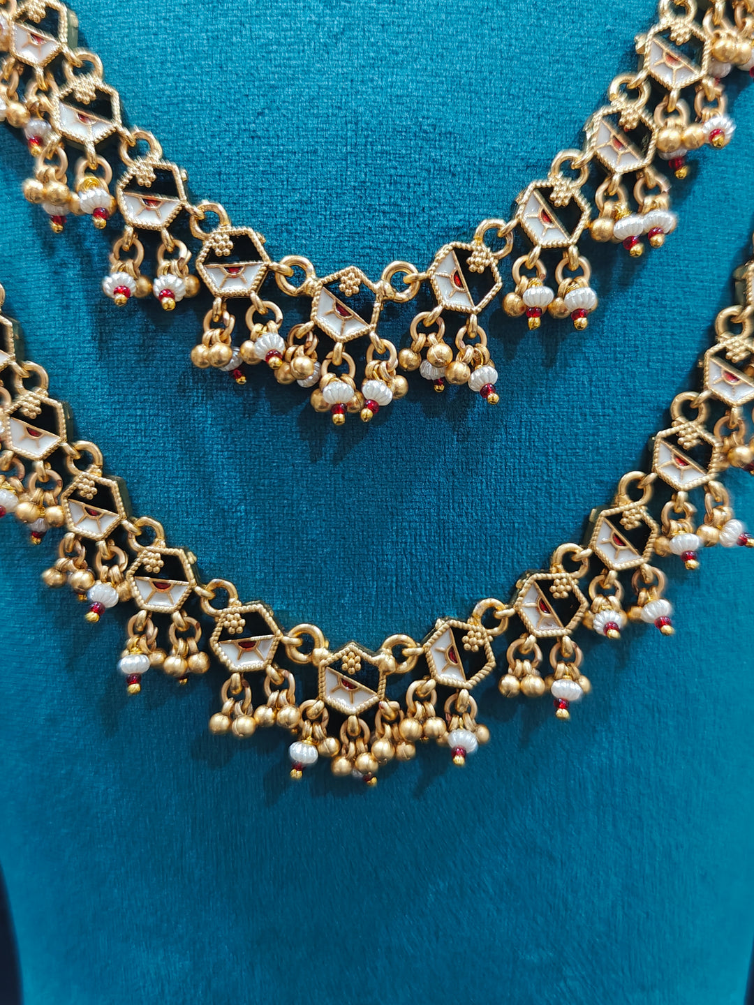Close-up of an ornate traditional Dark Pink Heritage gold Long Layered jewellery set and earrings with Colored Stones and Beads. Festive celebration outfit paired with a handcrafted heritage jewelry set. Festive  outfit styled with a royal heritage necklace.