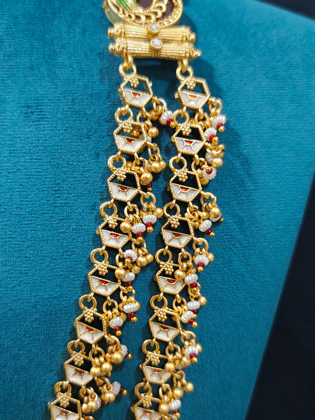 Close-up of an ornate traditional Dark Pink Heritage gold Long Layered jewellery set and earrings with Colored Stones and Beads. Festive celebration outfit paired with a handcrafted heritage jewelry set. Festive  outfit styled with a royal heritage necklace.