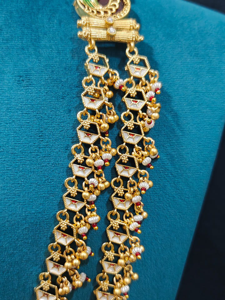 Close-up of an ornate traditional Dark Pink Heritage gold Long Layered jewellery set and earrings with Colored Stones and Beads. Festive celebration outfit paired with a handcrafted heritage jewelry set. Festive  outfit styled with a royal heritage necklace.