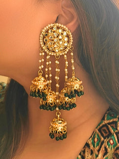 Close-up of a woman wearing an ornate traditional (Gold Polish) Dark Green Long  Earrings with Kundan, Pearls and Dark Green Beads Mehendi ceremony look completed with a handcrafted Kundan Earrings. Wedding celebration look enhanced with a statement Kundan Earrings.
