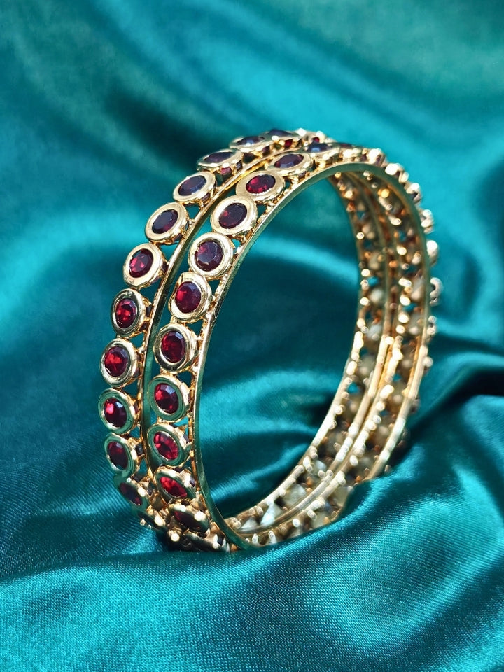 Close-up of an ornate traditional (Gold Polish) Maroon Bangles Set with Maroon Colored Stones. Festive celebration look enhanced with artificial Colored Stone bangles. Woman stacking artificial Colored Stone bangles for a festive Diwali celebration.
