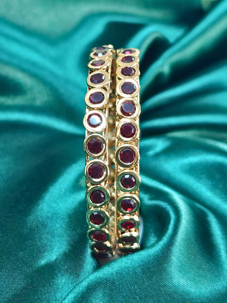 Close-up of an ornate traditional (Gold Polish) Maroon Bangles Set with Maroon Colored Stones. Festive celebration look enhanced with artificial Colored Stone bangles. Woman stacking artificial Colored Stone bangles for a festive Diwali celebration.
