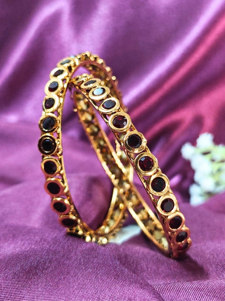 Close-up of an ornate traditional (Gold Polish) Maroon Bangles Set with Maroon Colored Stones. Festive celebration look enhanced with artificial Colored Stone bangles. Woman stacking artificial Colored Stone bangles for a festive Diwali celebration.