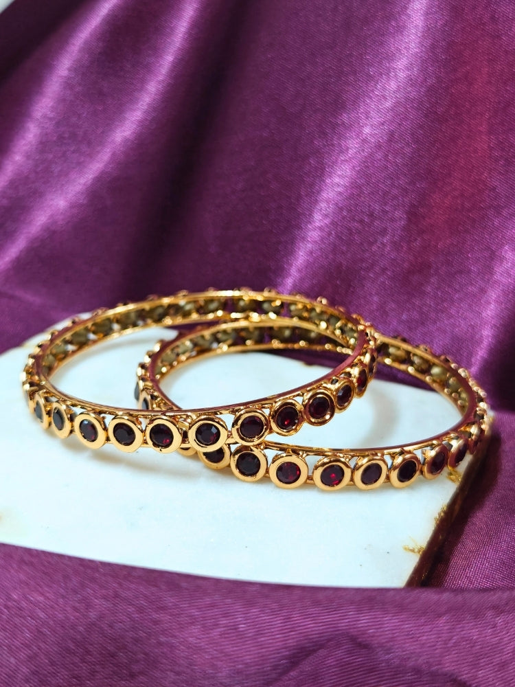 Close-up of an ornate traditional (Gold Polish) Maroon Bangles Set with Maroon Colored Stones. Festive celebration look enhanced with artificial Colored Stone bangles. Woman stacking artificial Colored Stone bangles for a festive Diwali celebration.