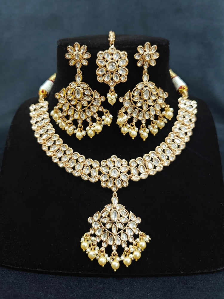 Close-up of an ornate traditional (Gold Polish) Collar White jewellery set and earrings and maangtikka with Polki and Pearl. Wedding guest wearing a statement Polki artificial necklace for a reception party. Woman styling a premium Polki imitation necklace for wedding celebrations.