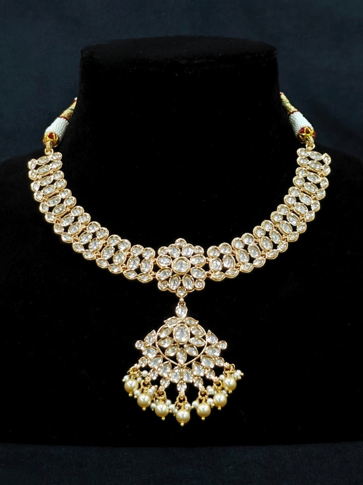 Close-up of an ornate traditional (Gold Polish) Collar White jewellery set and earrings and maangtikka with Polki and Pearl. Wedding guest wearing a statement Polki artificial necklace for a reception party. Woman styling a premium Polki imitation necklace for wedding celebrations.