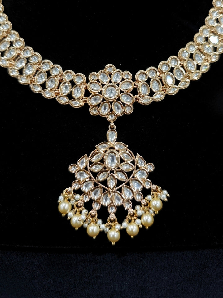 Close-up of an ornate traditional (Gold Polish) Collar White jewellery set and earrings and maangtikka with Polki and Pearl. Wedding guest wearing a statement Polki artificial necklace for a reception party. Woman styling a premium Polki imitation necklace for wedding celebrations.