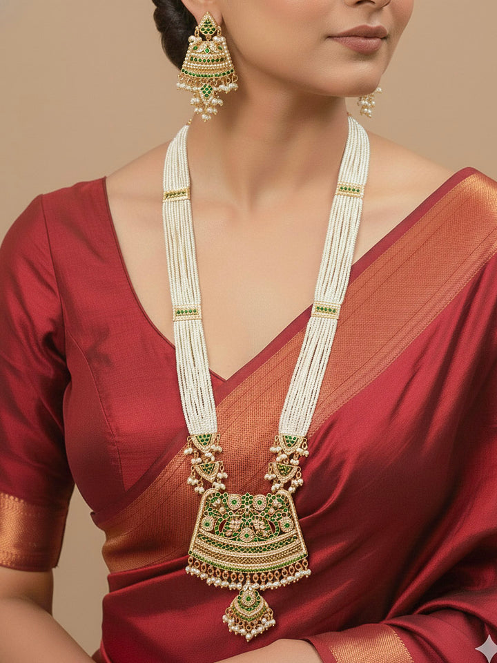 Close-up of a woman wearing an ornate traditional long jadau gold jewellery set and jadau earrings with pearls and gemstones. Perfect Jadau necklace set for weddings and festivals. 
