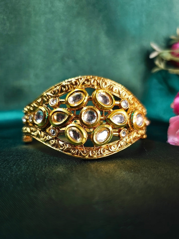 Golden Kundan Bracelet for weddings and festivals set on green background with pink flowers. 