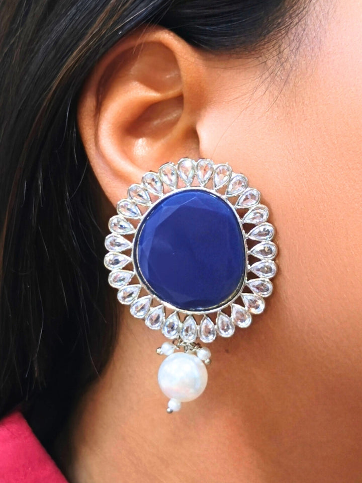 A close-up of a womans ear wearing Pamela Pink Earrings, which feature an oval shaped Pink colored stone,  American Diamond border and a dangling white pearl-perfect for pairing with your wedding ceremony dress.