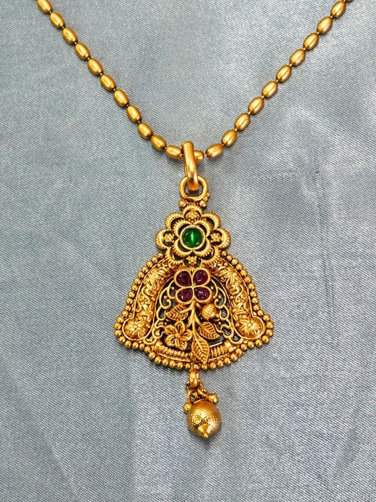 Close-up of an ornate traditional (Gold Polish) jewellery set and earrings with Pink & Green Colored Stones. Saree look completed with an elegant Colored Stone artificial jewelry piece. Festive Diwali outfit paired with a colorful Colored Stone necklace.